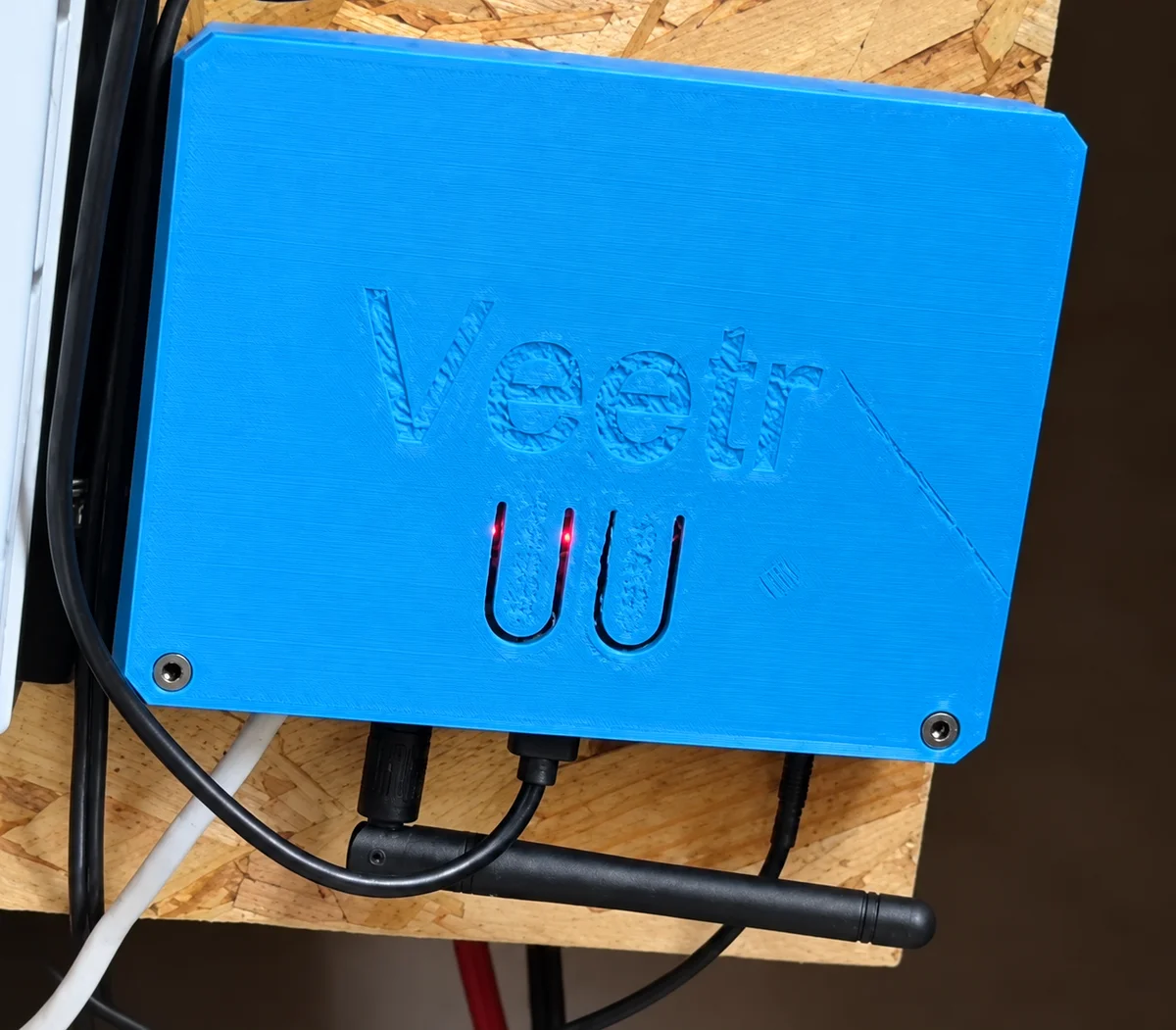 Modrá krabička Veetr z 3D tisku s kabely a externí anténou